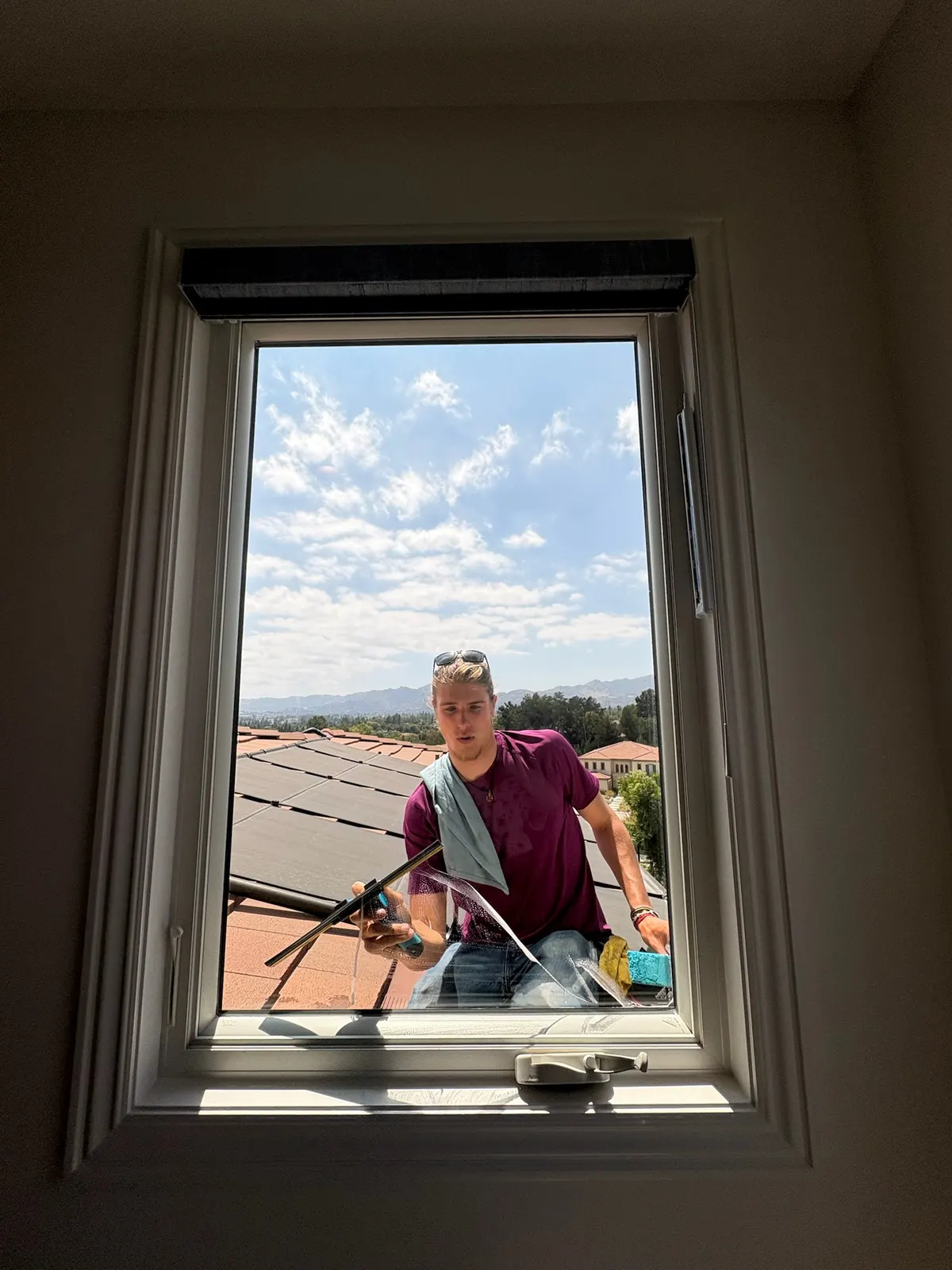 A Happy Gator team member squeegeeing an upstairs window from the roof
