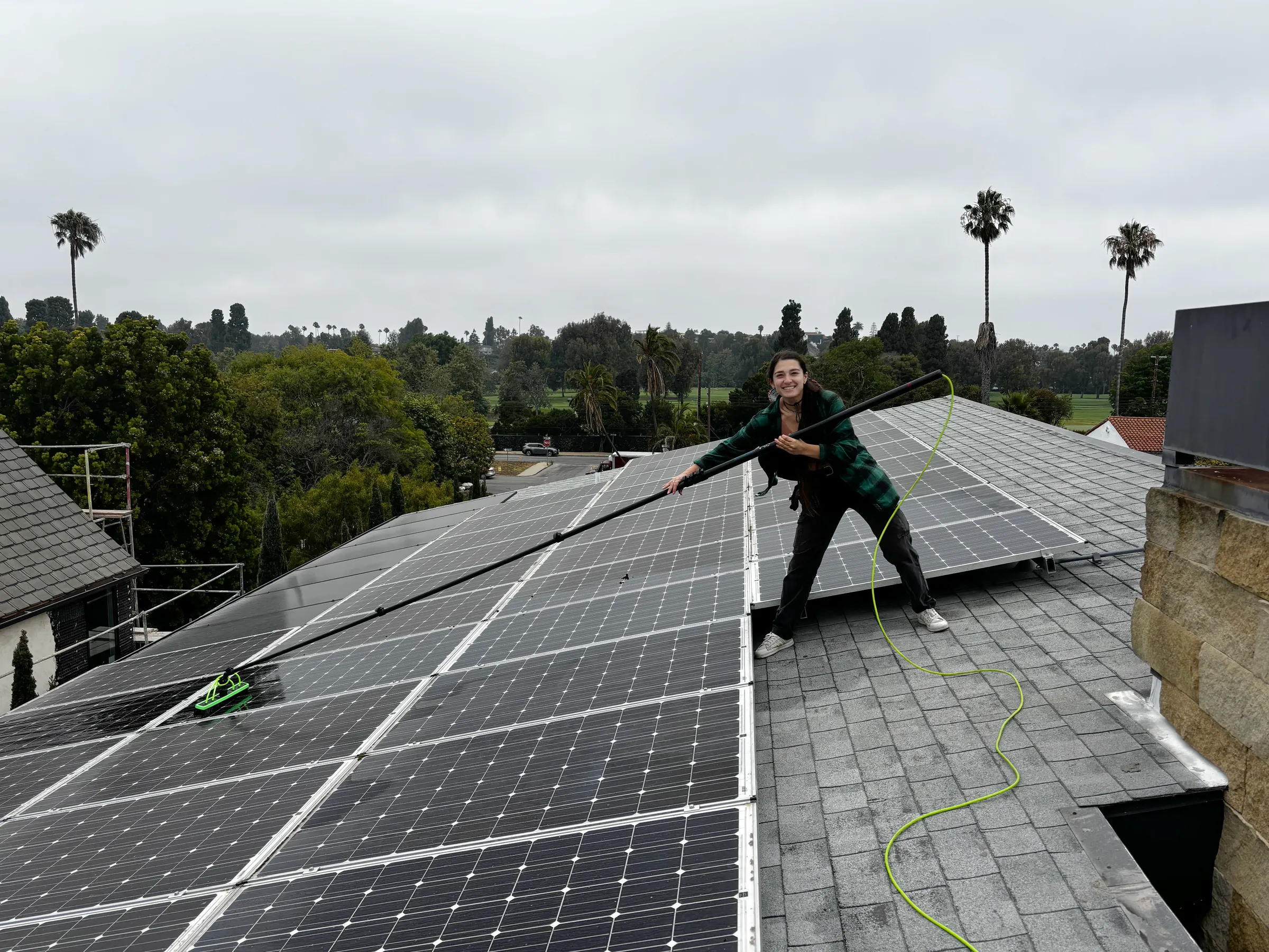 Gal of Happy Gator cleaning solar panels on a rooftop with a water-fed pole