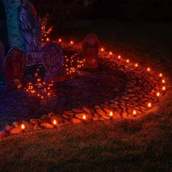 A curved front walkway lined with glowing orange lights and Halloween tombstone decor