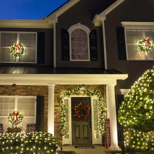Lit wreaths hung on a home's windows and front door