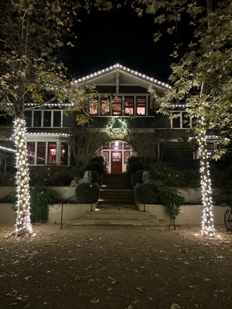 A Westside craftsman home outlined in Christmas lights with wrapped trees framing the walkway